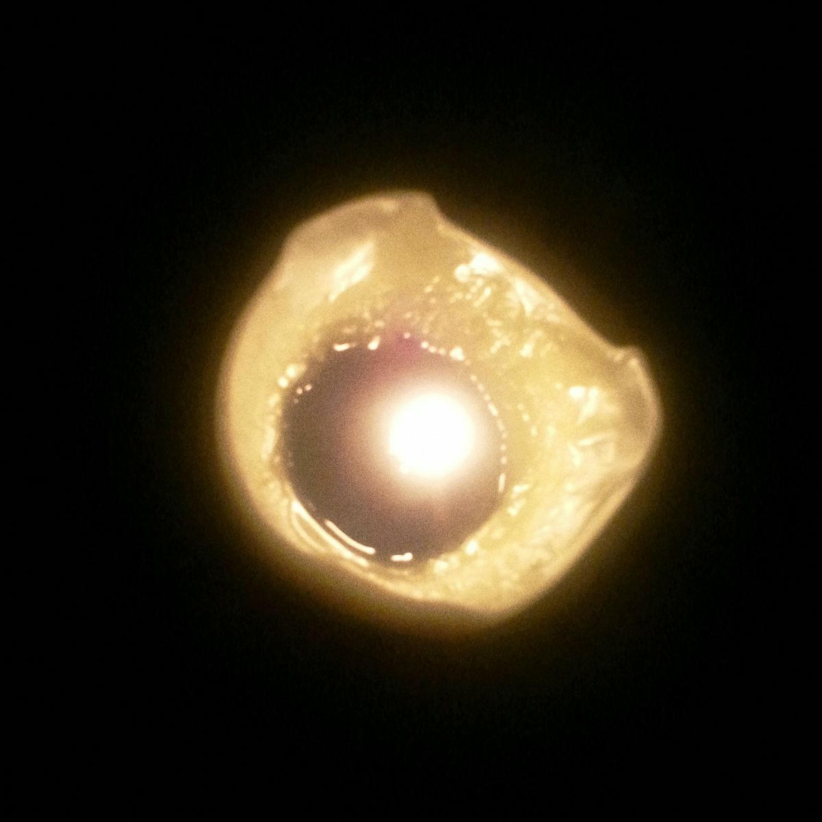 En gros plan, vue de haut dans la noirceur complète, une chandelle et sa flamme.