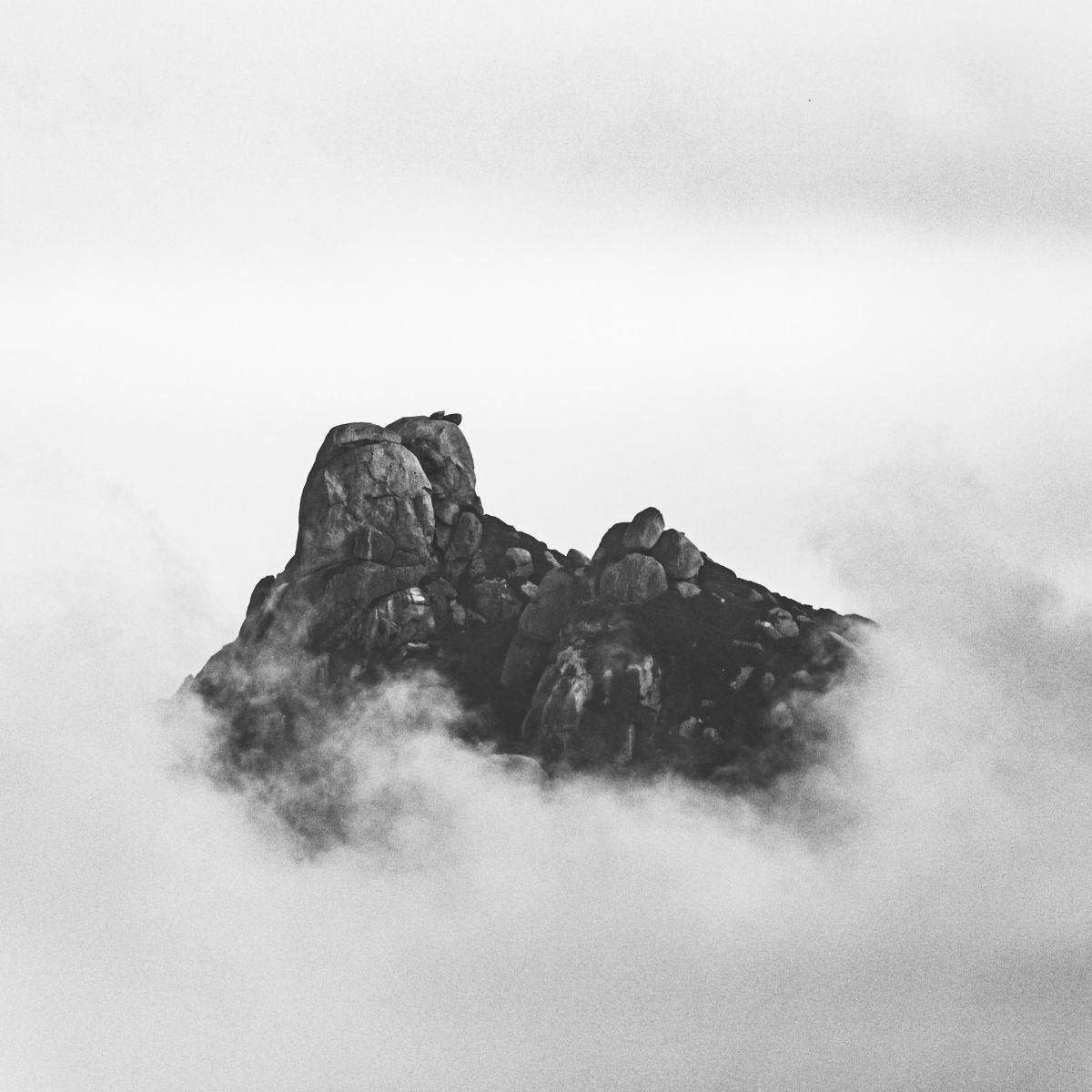 Vue du ciel, une mystérieuse formation rocheuse perce les nuages.